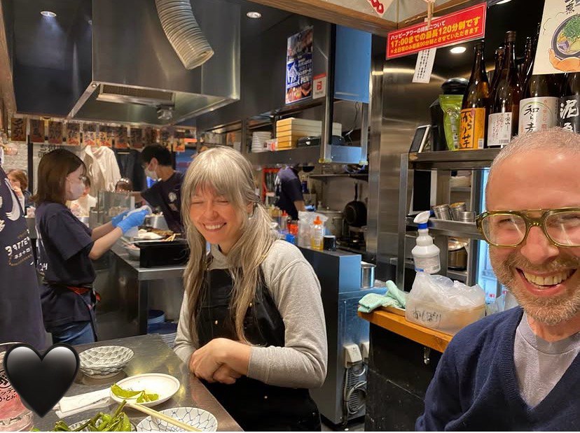 Tora and Tom smiling at a busy restaurant counter